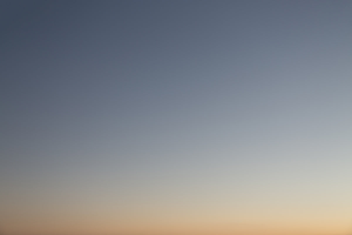 a plane flying in the sky at sunset